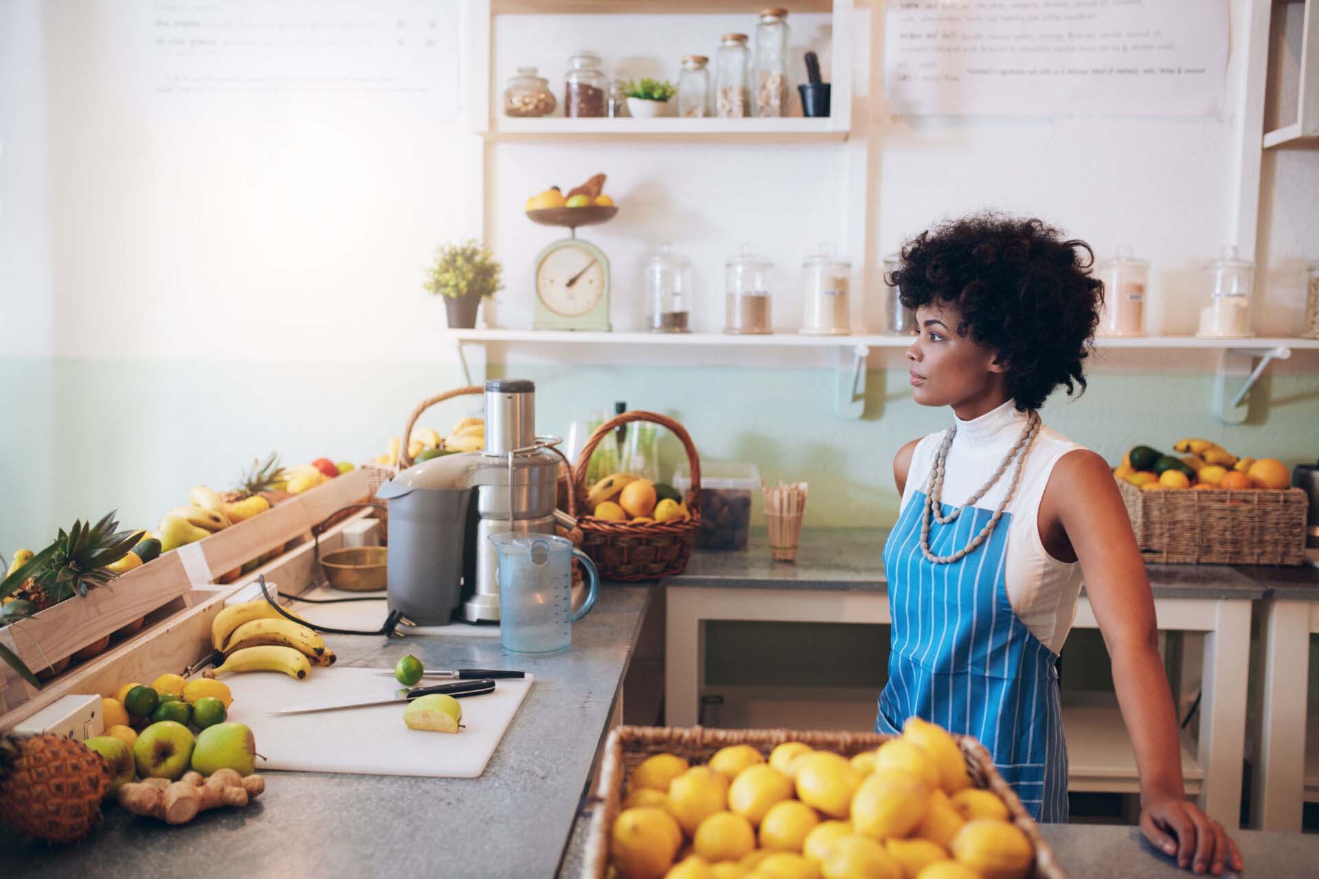 Young female bartender standing at juice bar counter Insurance for Juice Bars