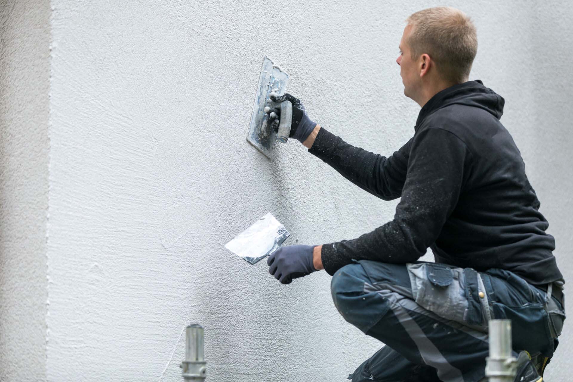 construction worker putting decorative plaster on house exterior Insurance for Stucco and Plastering Contractors