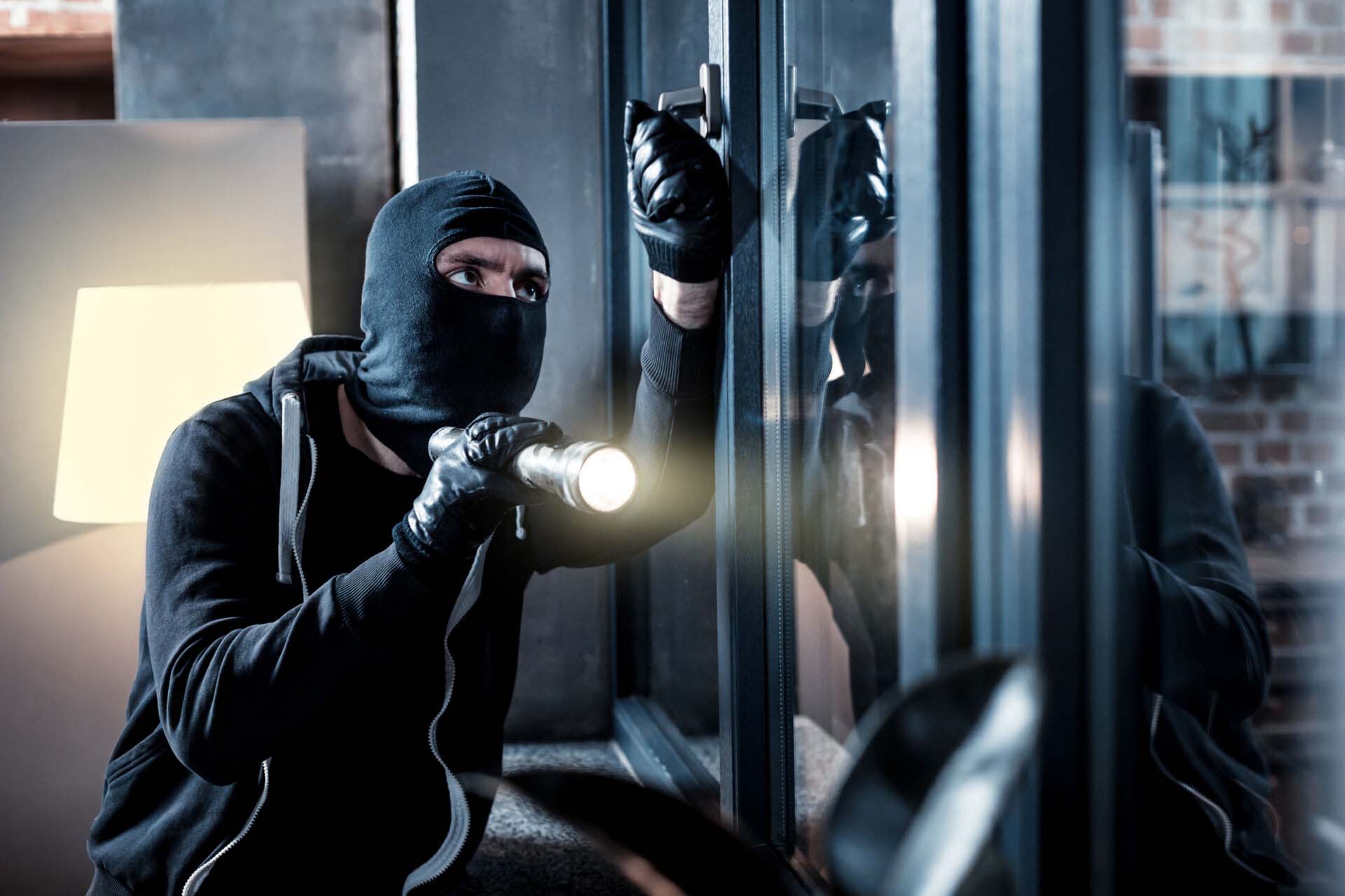 Masked burglar breaking into the house Commercial Crime Insurance