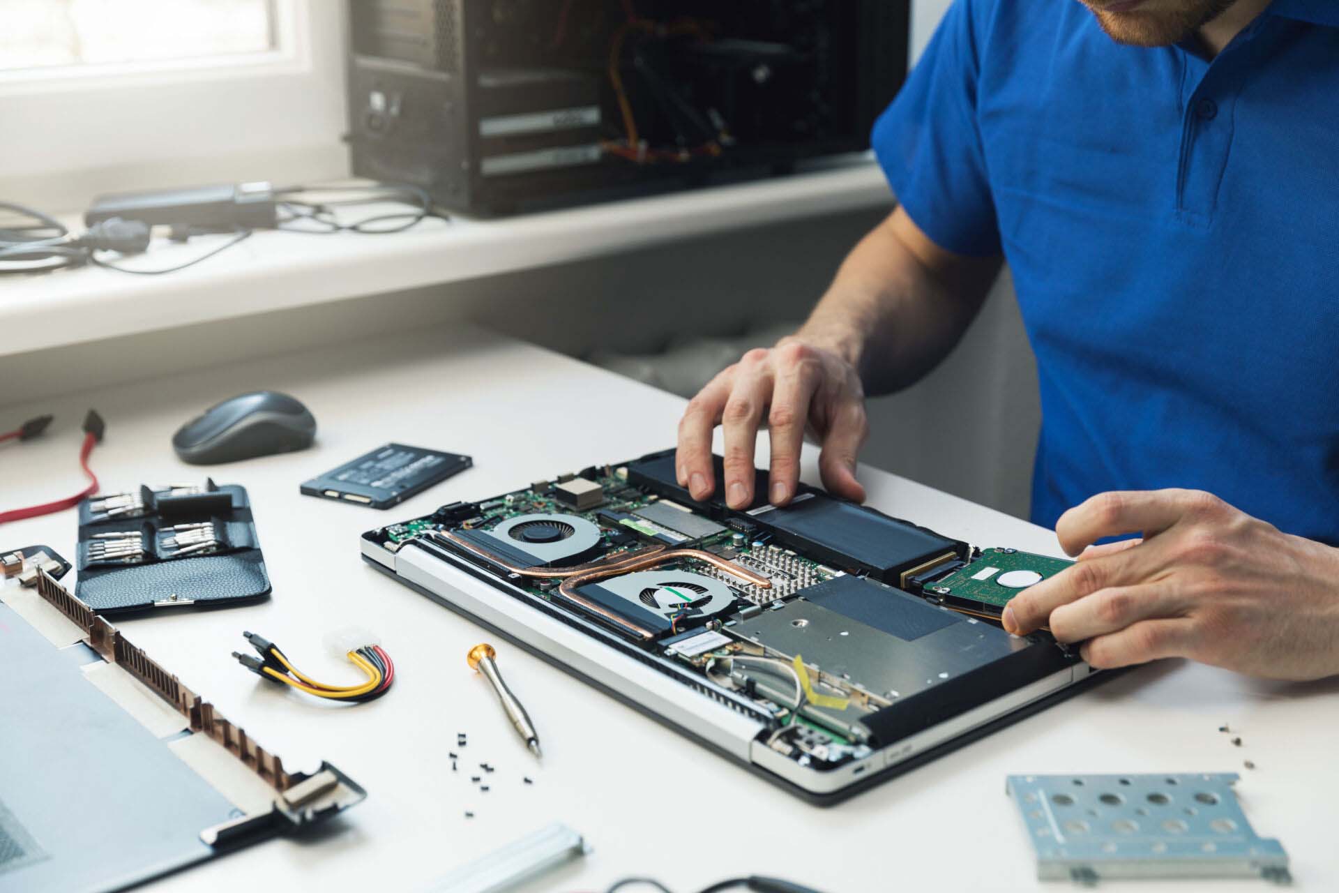 computer repairman installing new hard disk drive in laptop Insurance for Computer and Electronics Stores