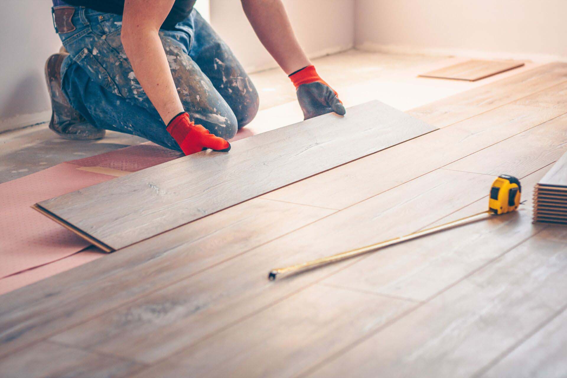 Worker professionally installs floor boards Insurance for Flooring Installation Contractors