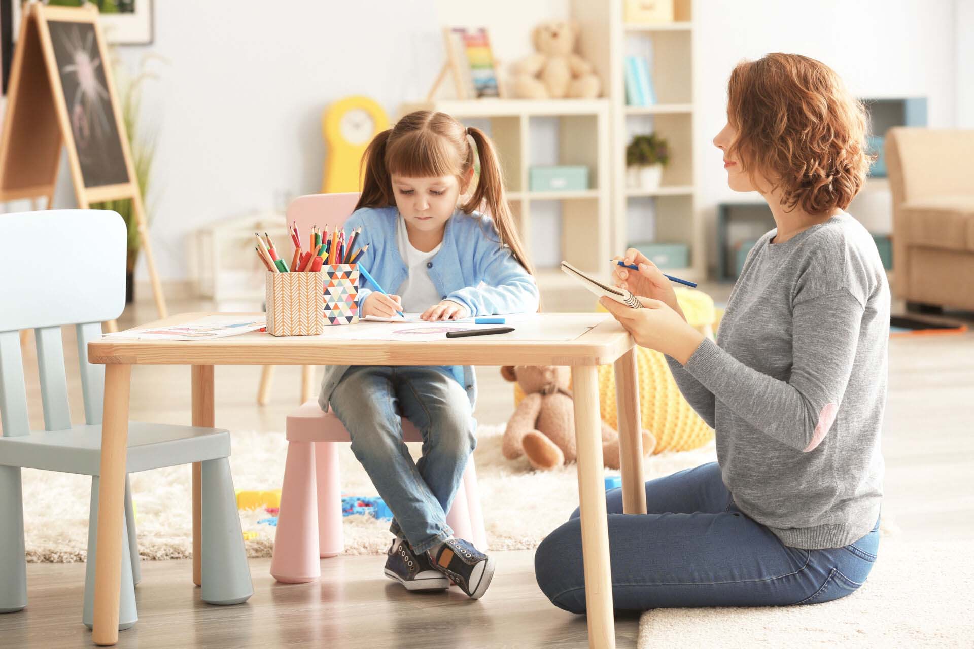 Female psychologist with cute little girl during art therapy Insurance for Expressive and Creative Arts Therapists