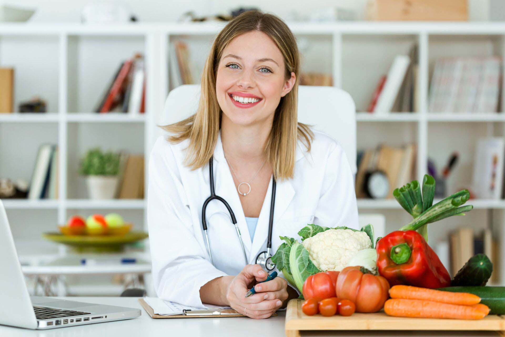 Beautiful smiling nutritionist looking at camera and showing hea Insurance for Nutritionists
