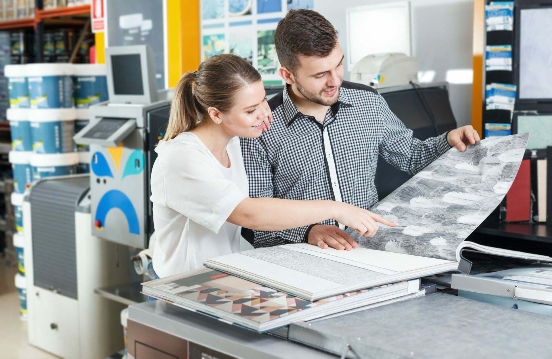 Smiling family couple looking samples of designer wallpaper Insurance for Paint and Wallpaper Stores