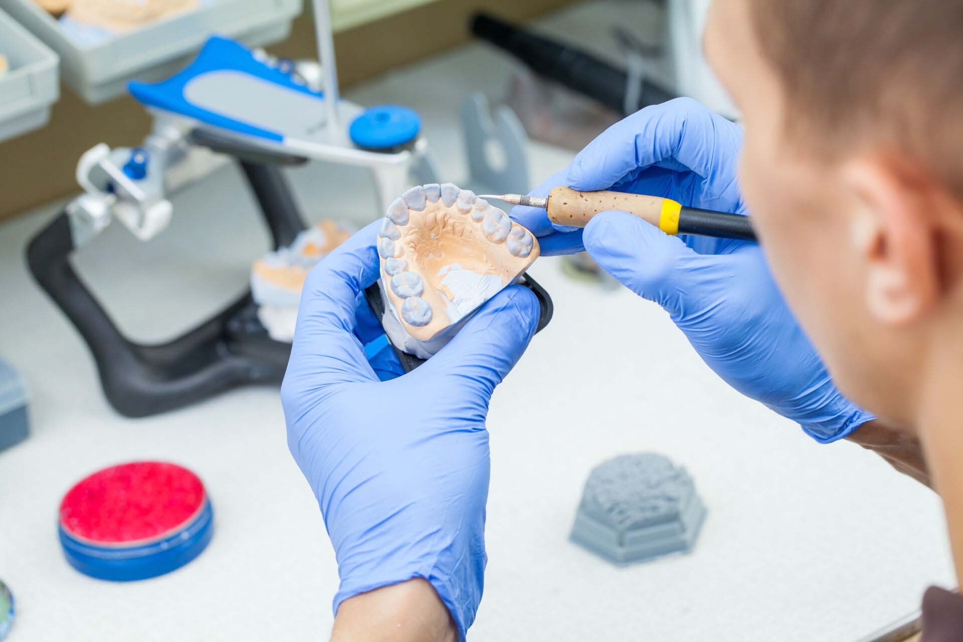 A dental technician dentist working with prostheses in a laboratory with wax on a jaw model Insurance for Dental Labs