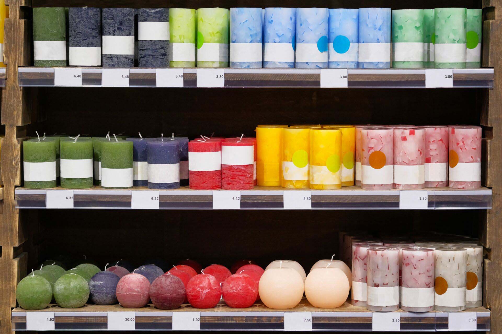 Candles for sale in a interior decorating store. Сoloured variety paraffin candles in cozy candle shop. Insurance for Candle Shops