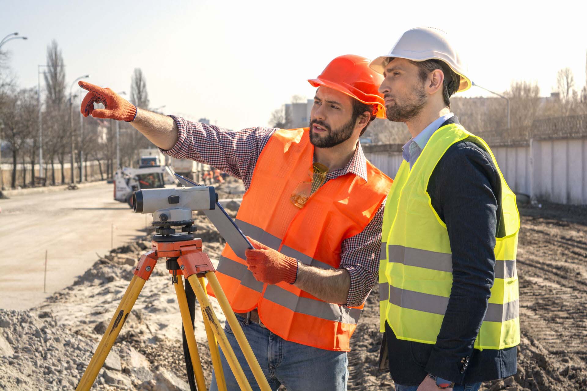 two male surveyor engineer with a device working on a construction site in a helmet Insurance for Land Surveyors