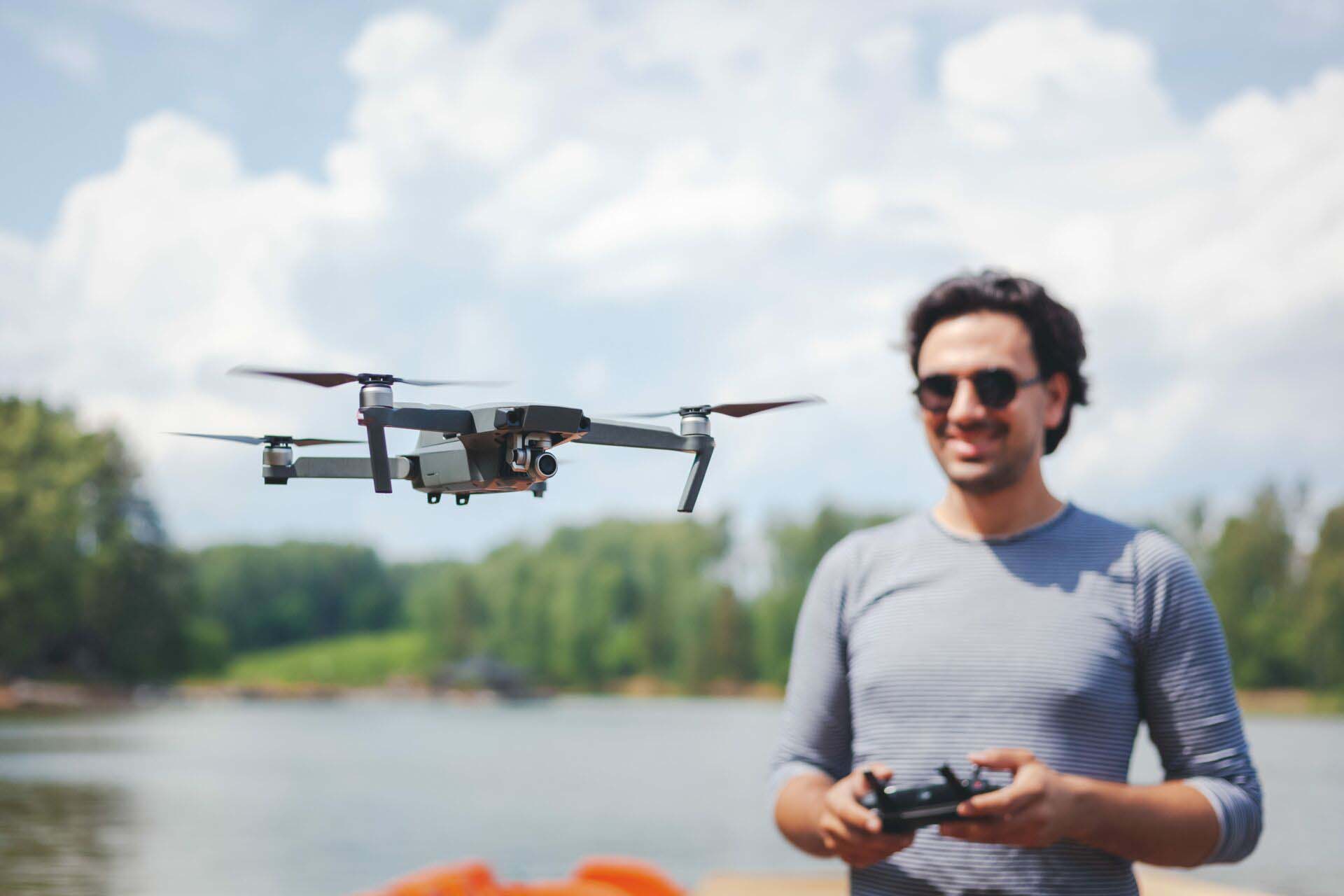 Young Man watching and navigating a flying drone in blue clear Sky Insurance for Drone Photographers