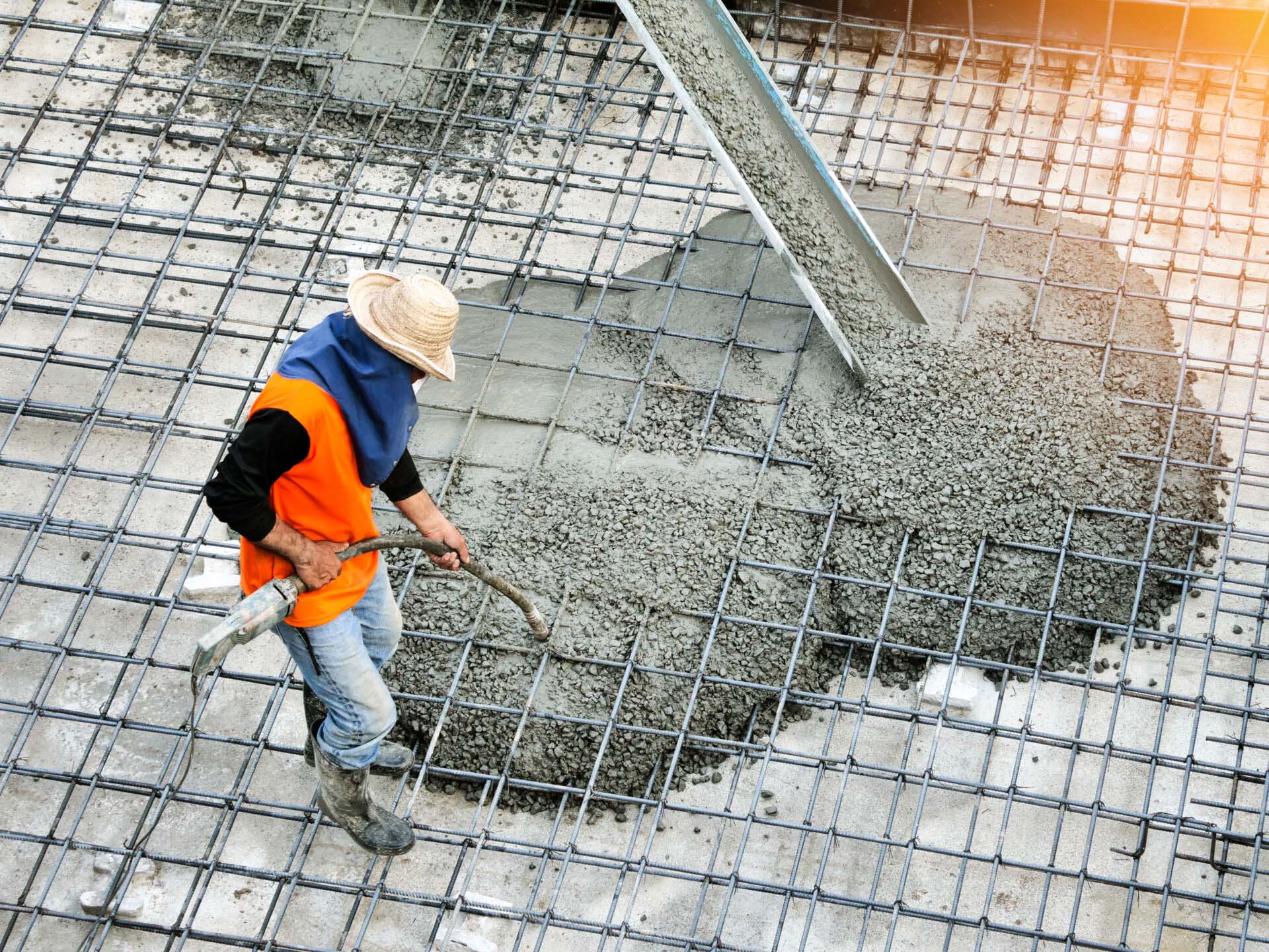 Top view of builders in orange shirt pouring concrete works on t Insurance for Concrete Contractors