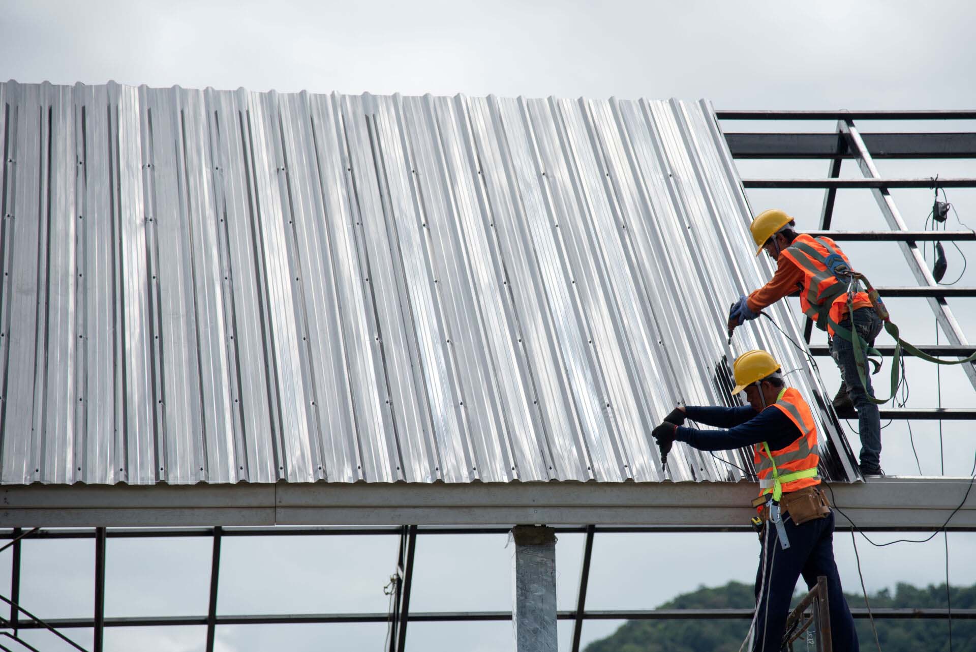 2 workers for construction, installing metal roofing tools, sheet metal New electric drill tool used on a new roof with metal sheets. Insurance for Sheet Metal Contractors