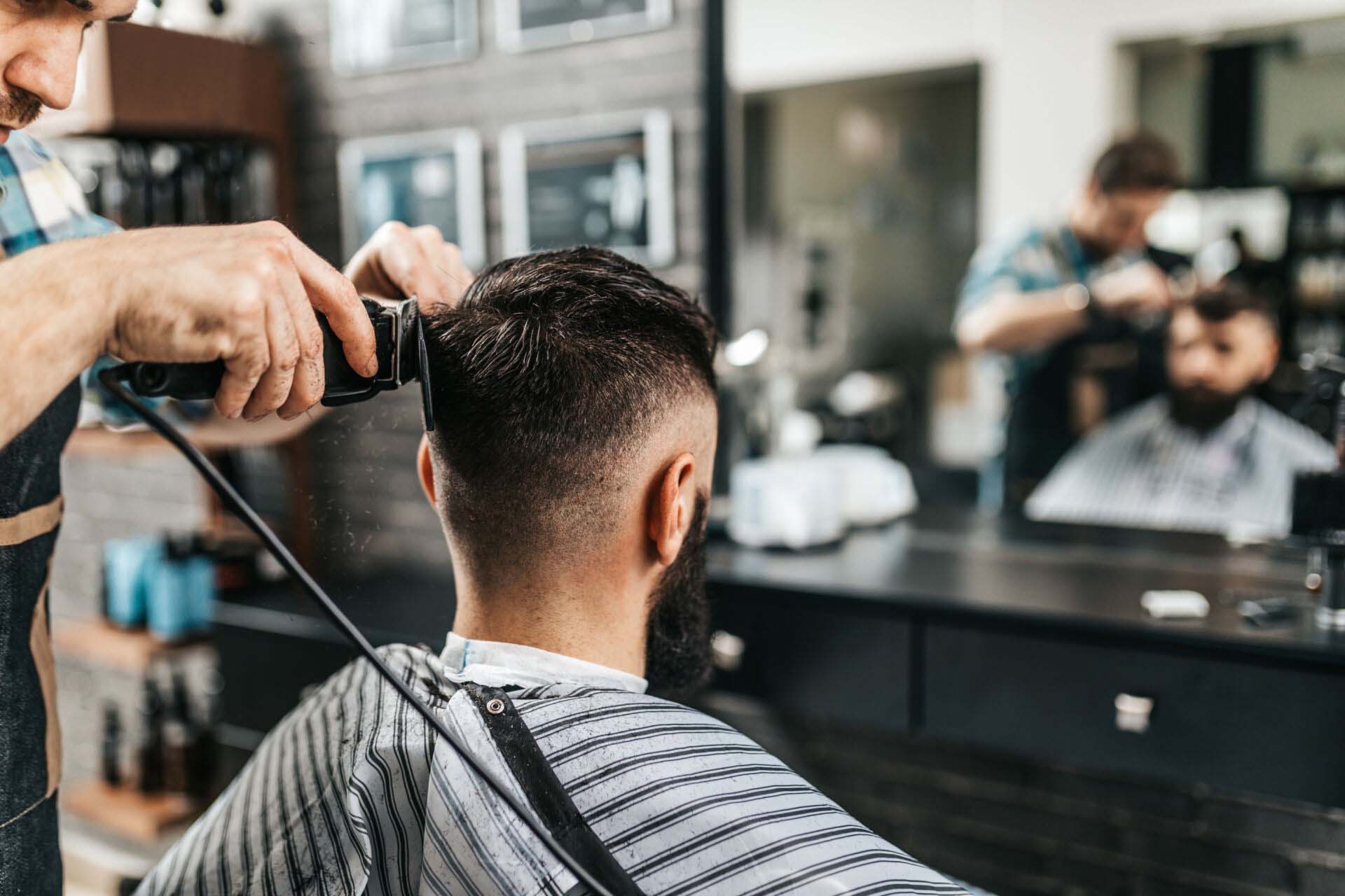 Good looking bearded man visiting hairstylist in barber shop. Insurance for Barber Shops