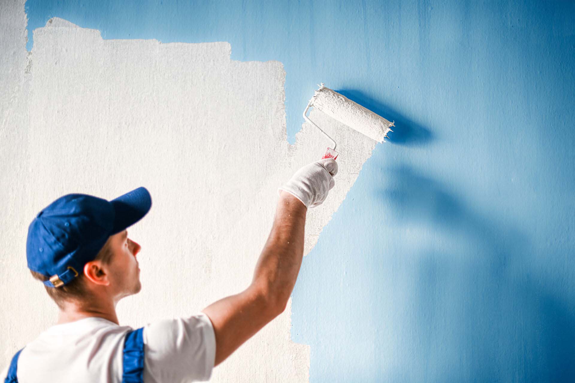 Painter painting a wall with paint roller. Insurance for Painting Businesses