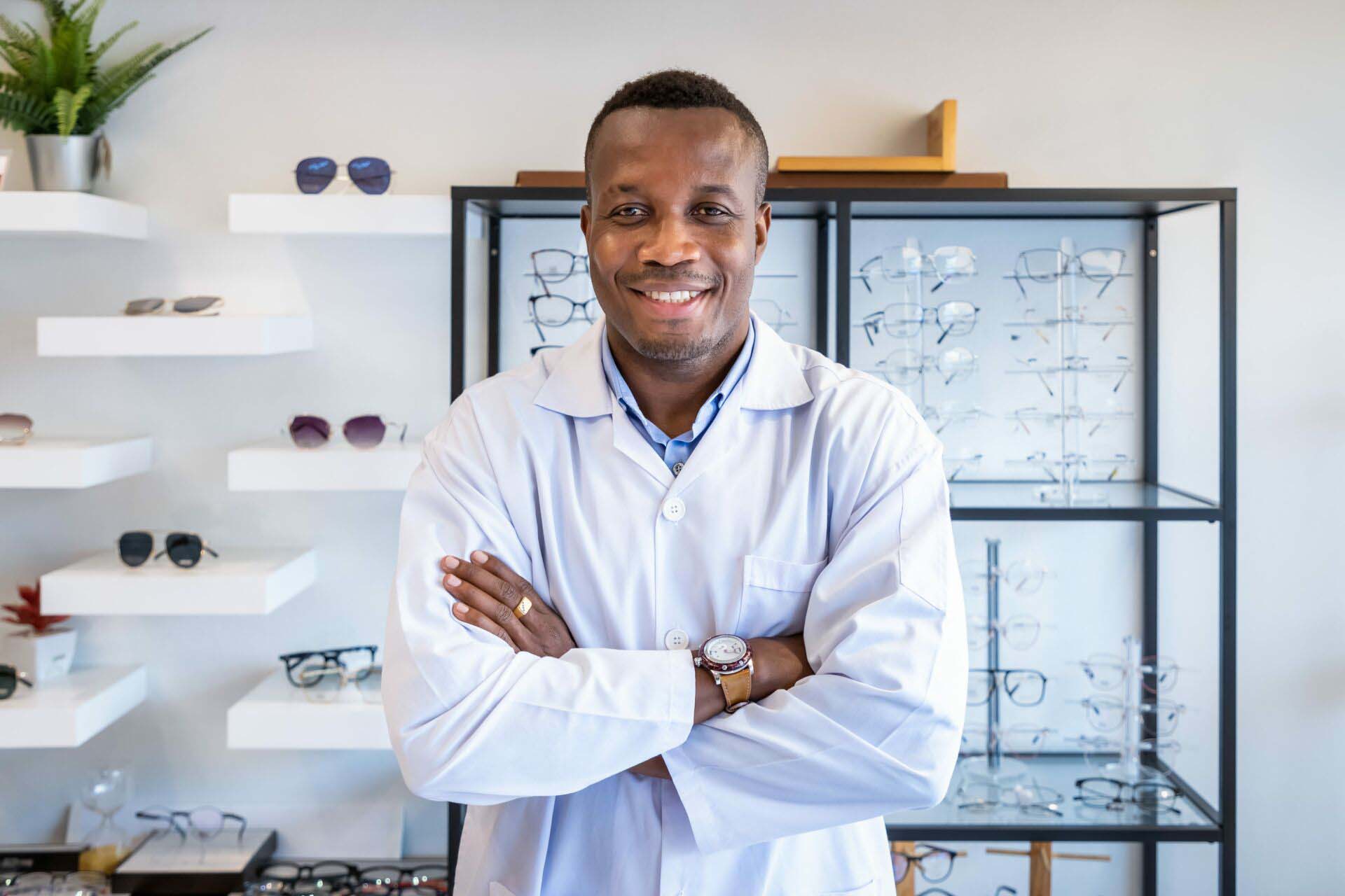 Portrait of African optician in optical shop store, cross arms, Insurance for Opticians