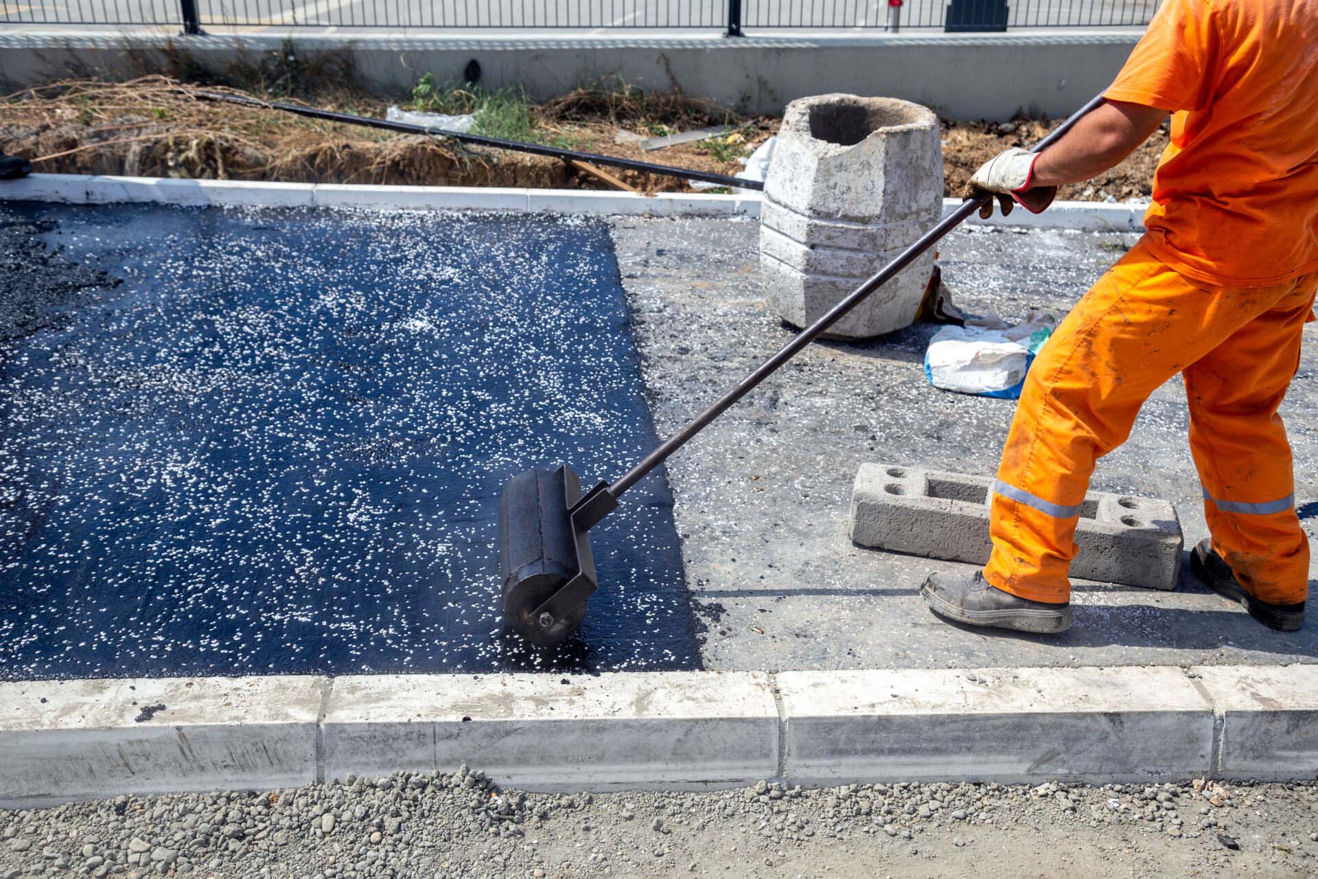 Worker push asphalt wooden hand roller on hot asphalt pavement Insurance for Paving Contractors