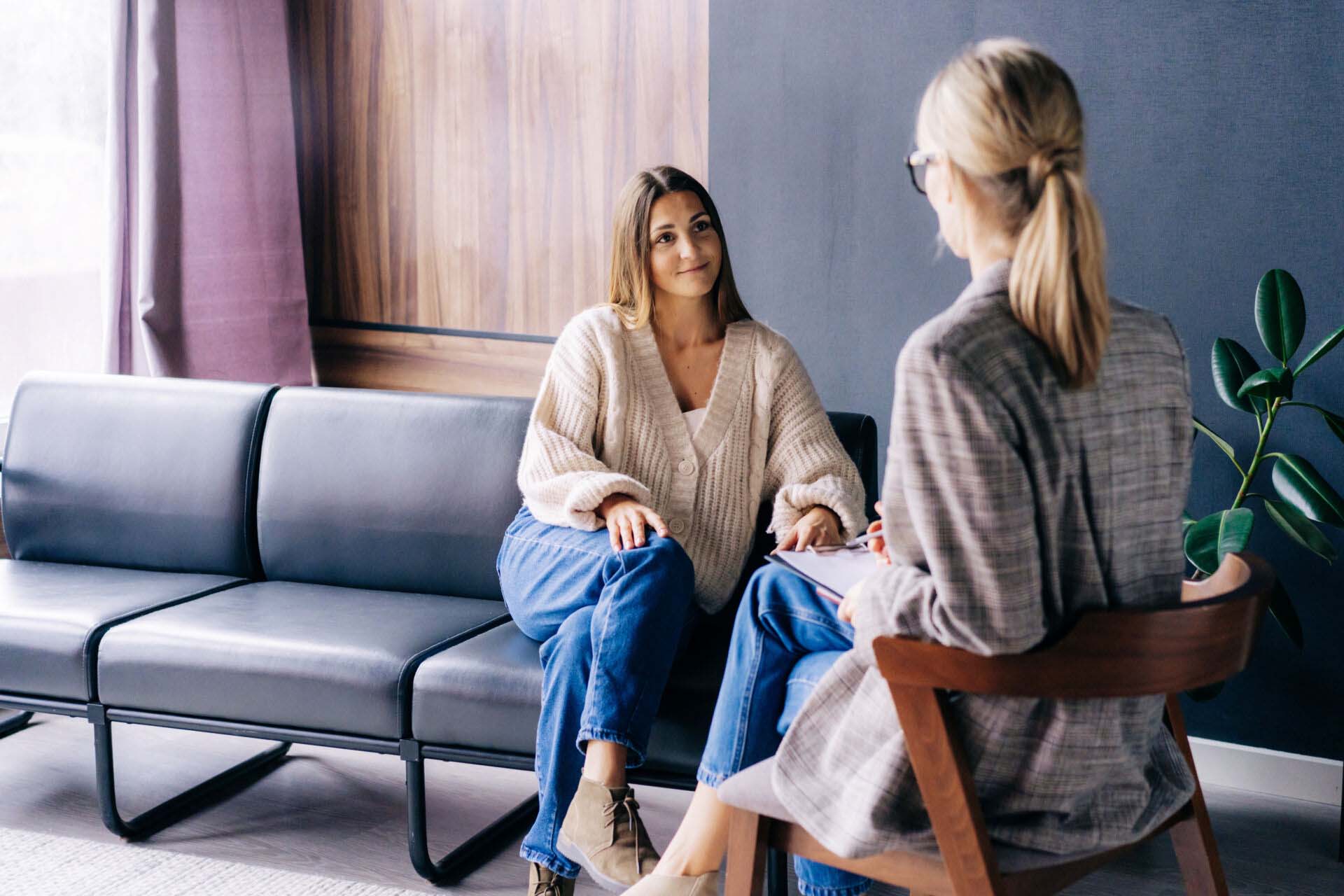 A smiling client is having a confidential conversation with a co Insurance for Wellness Counselors