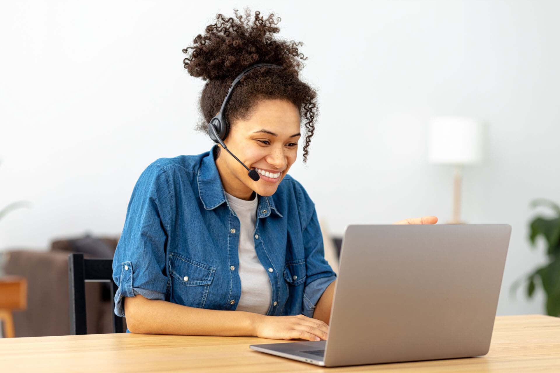 Successful African American woman in headset, office employee or call center worker sitting in a modern office talking, consulting client using video call, smile Insurance for Virtual Assistants