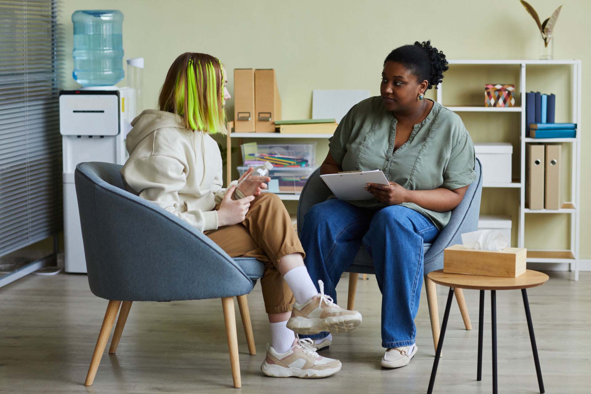 Woman social worker talking to teenage girl at office Insurance for School Counselors