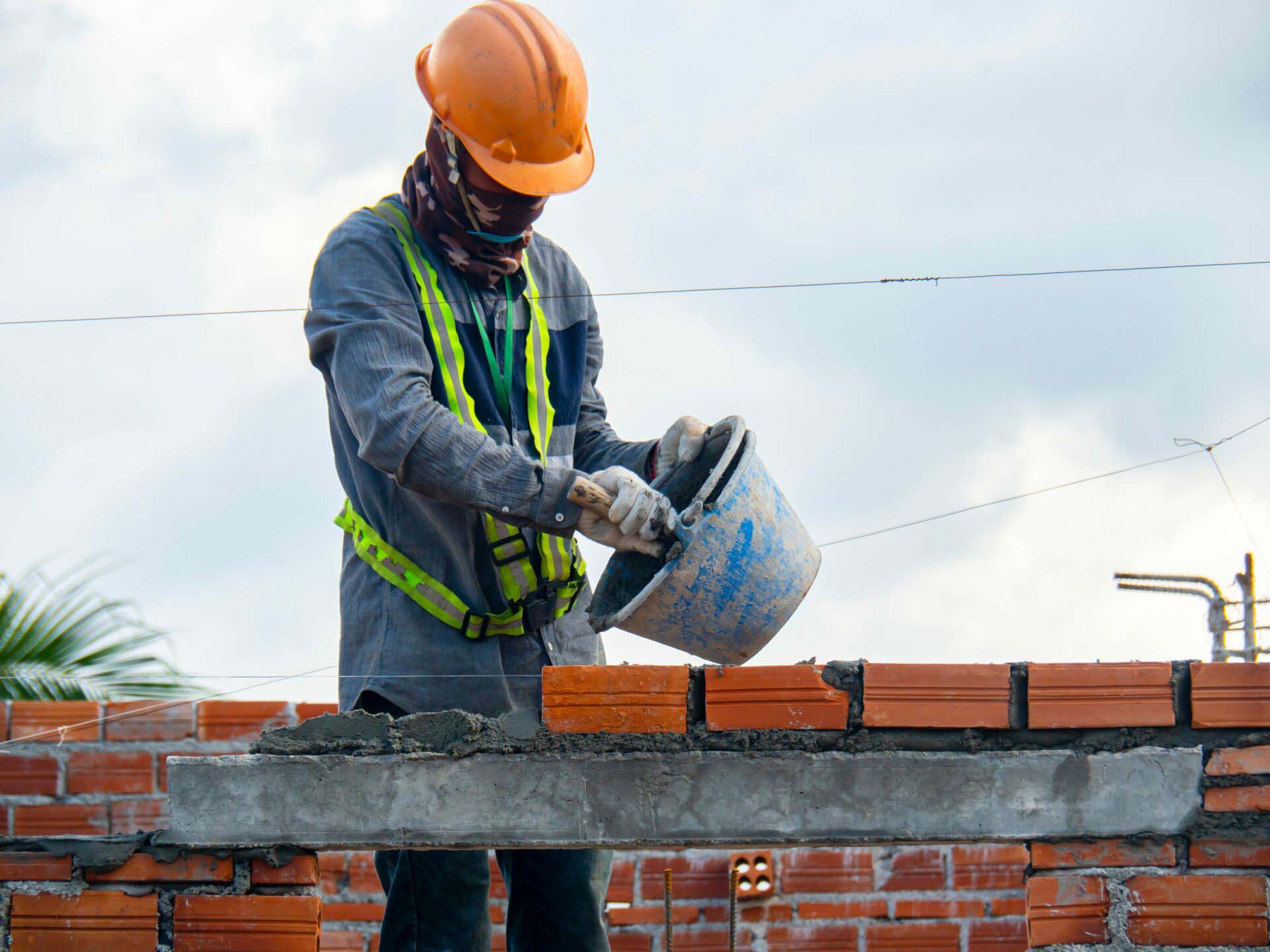 Masonry work, worker laying brick of an office building. Architectural work, under construction. Insurance for Masonry Contractors