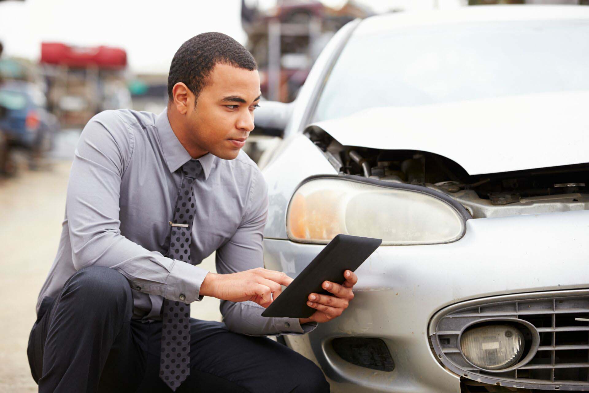 Loss Adjuster Using Digital Tablet In Car Wreck Inspection Insurance for Claims Adjusters