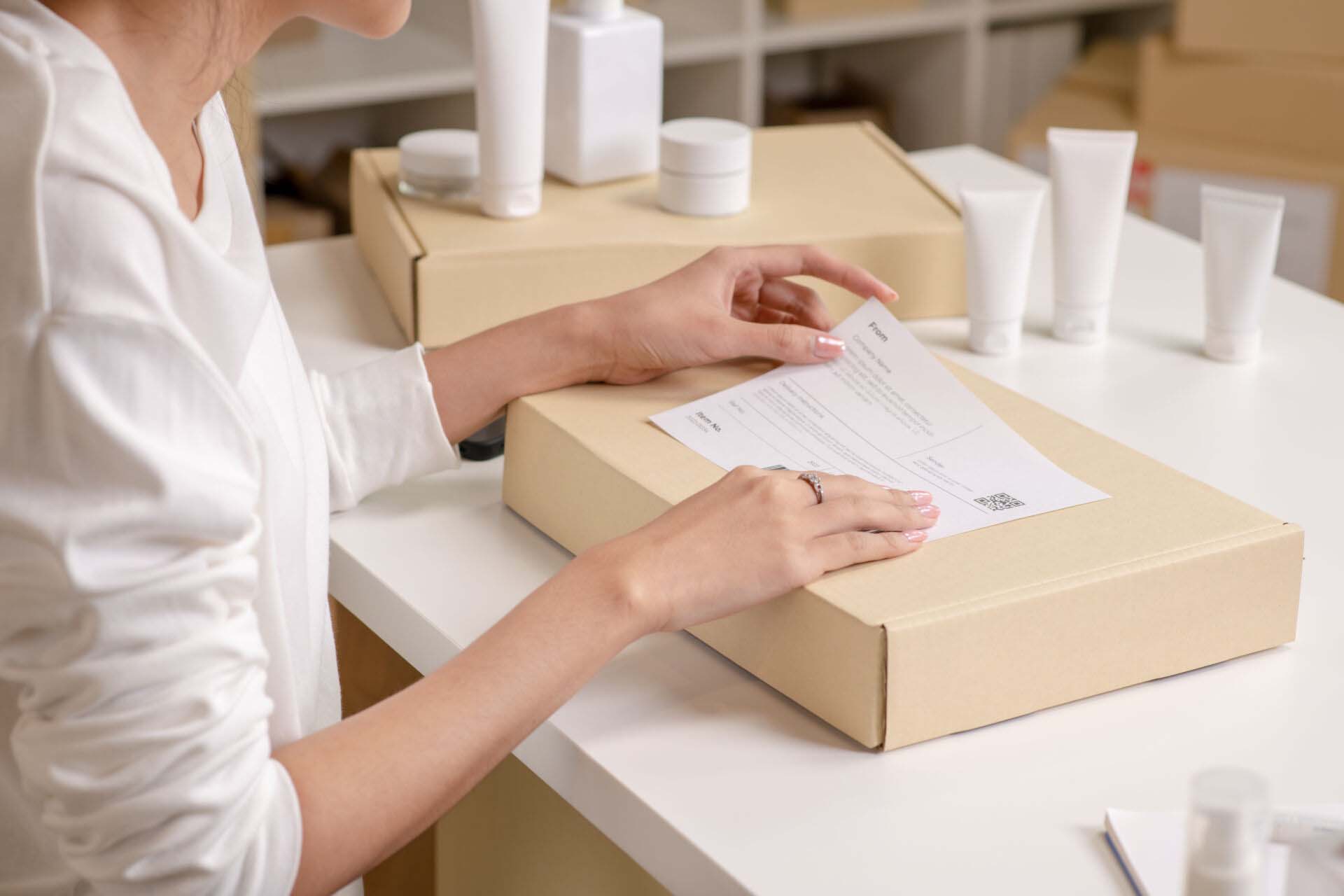 close-up shot of e-commerce seller packing an order, sticking a label, in a warehouse setting for an online beauty shop. Insurance for Cosmetics Wholesalers