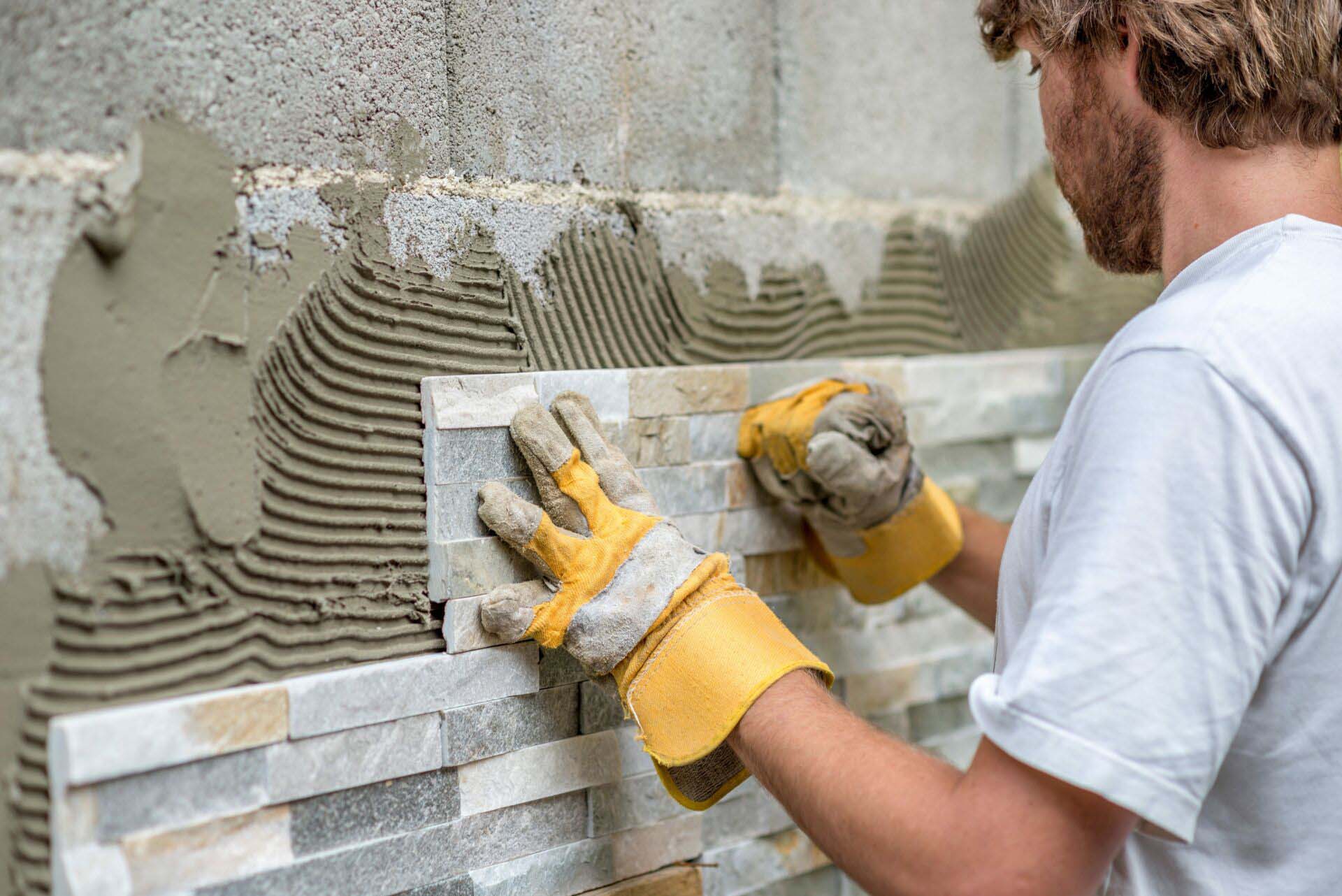 Man pressing an ornamental tile into a glue on a wall Insurance for Tile and Stone Installers