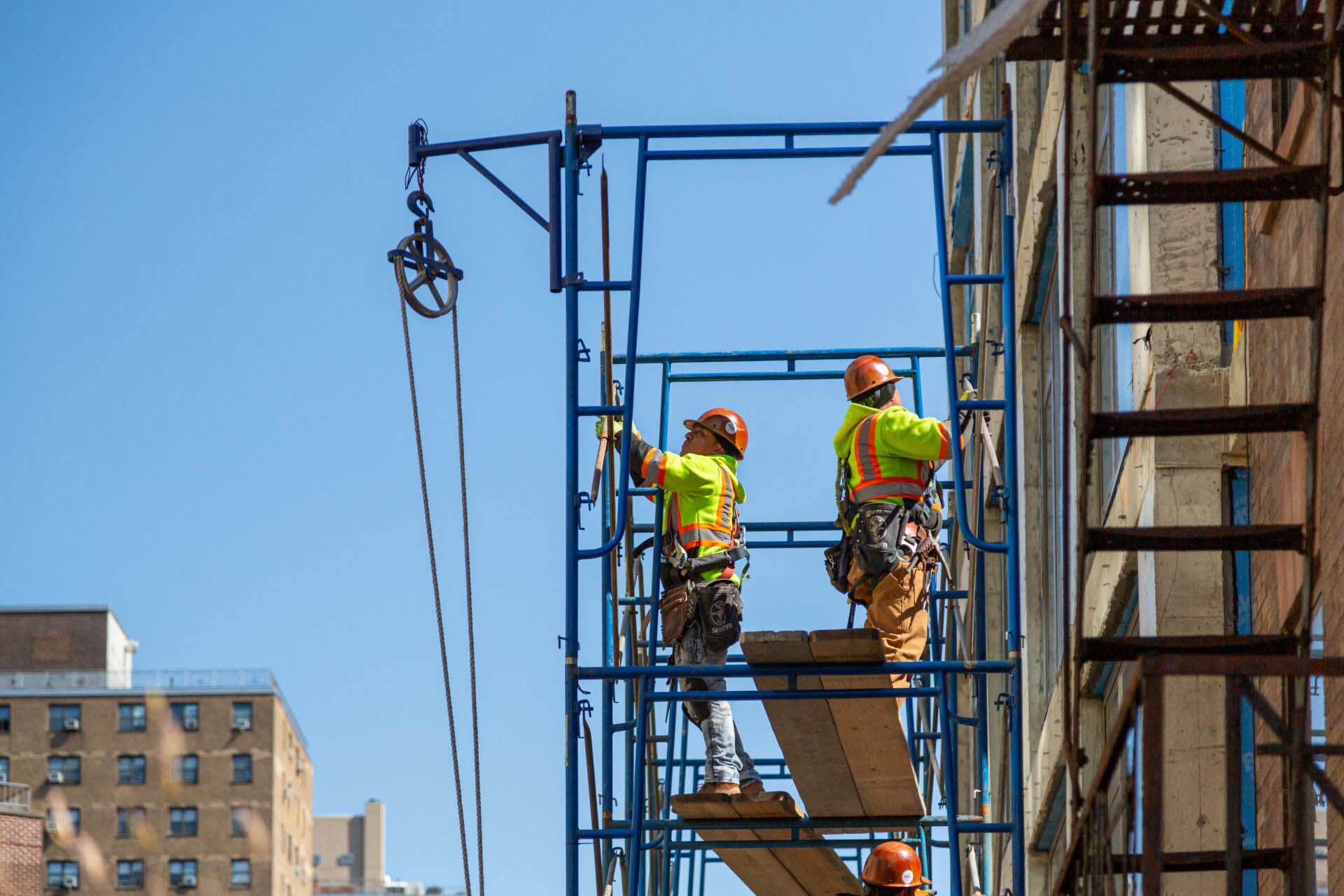 Construction workers at work on a skyscraper building renovation and construction site on a scaffold Insurance for Scaffolding Business