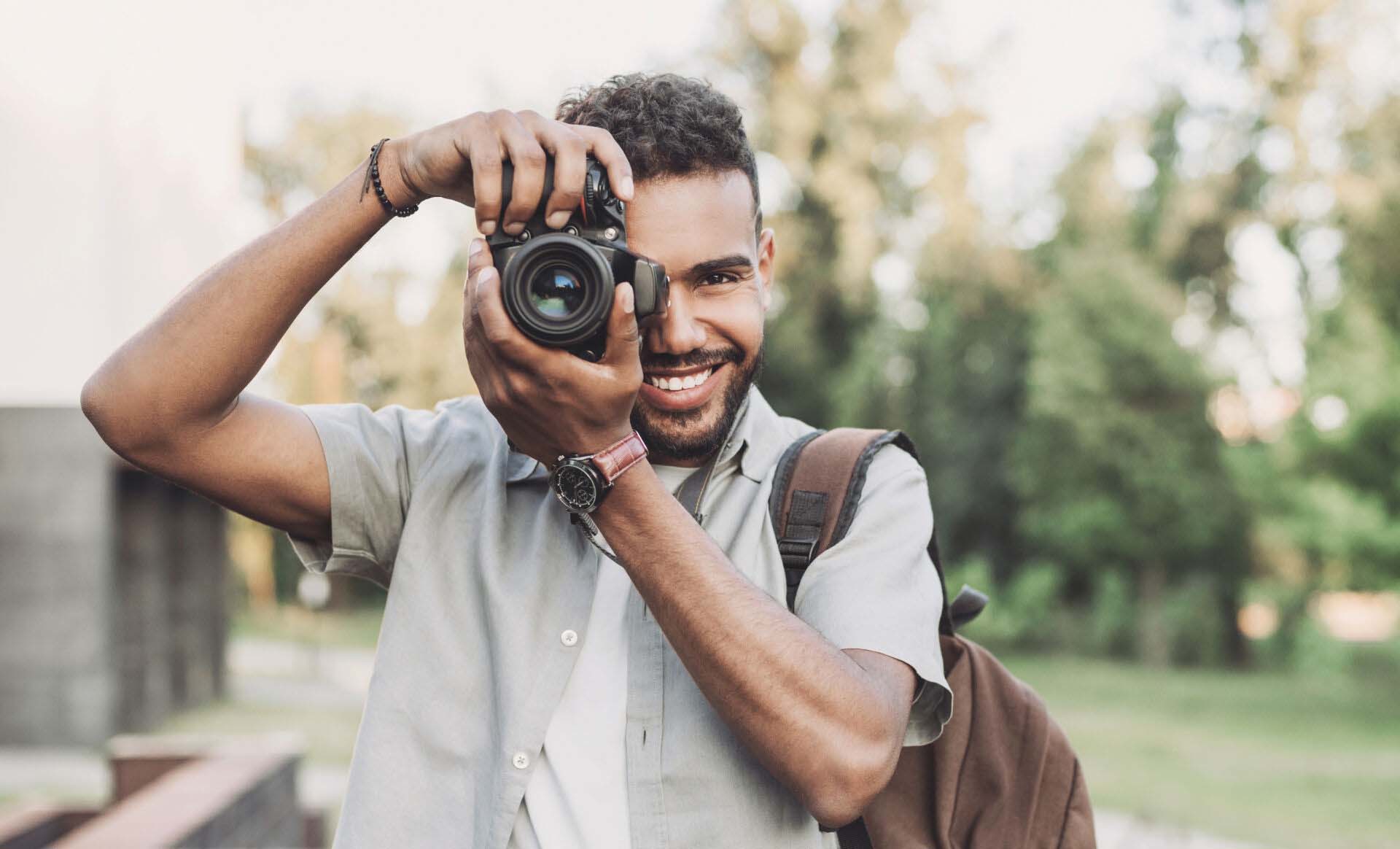 Young man photographer takes photographs with dslr camera in a c Insurance for Photographers