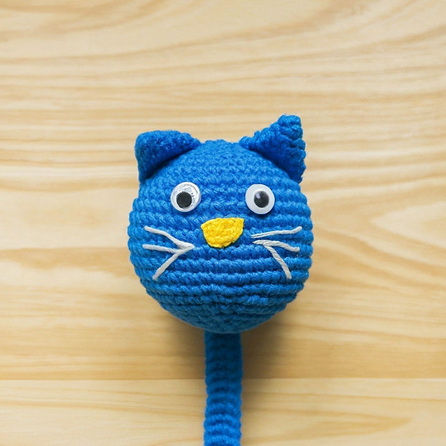 a cute cat made with blue and yellow yarn