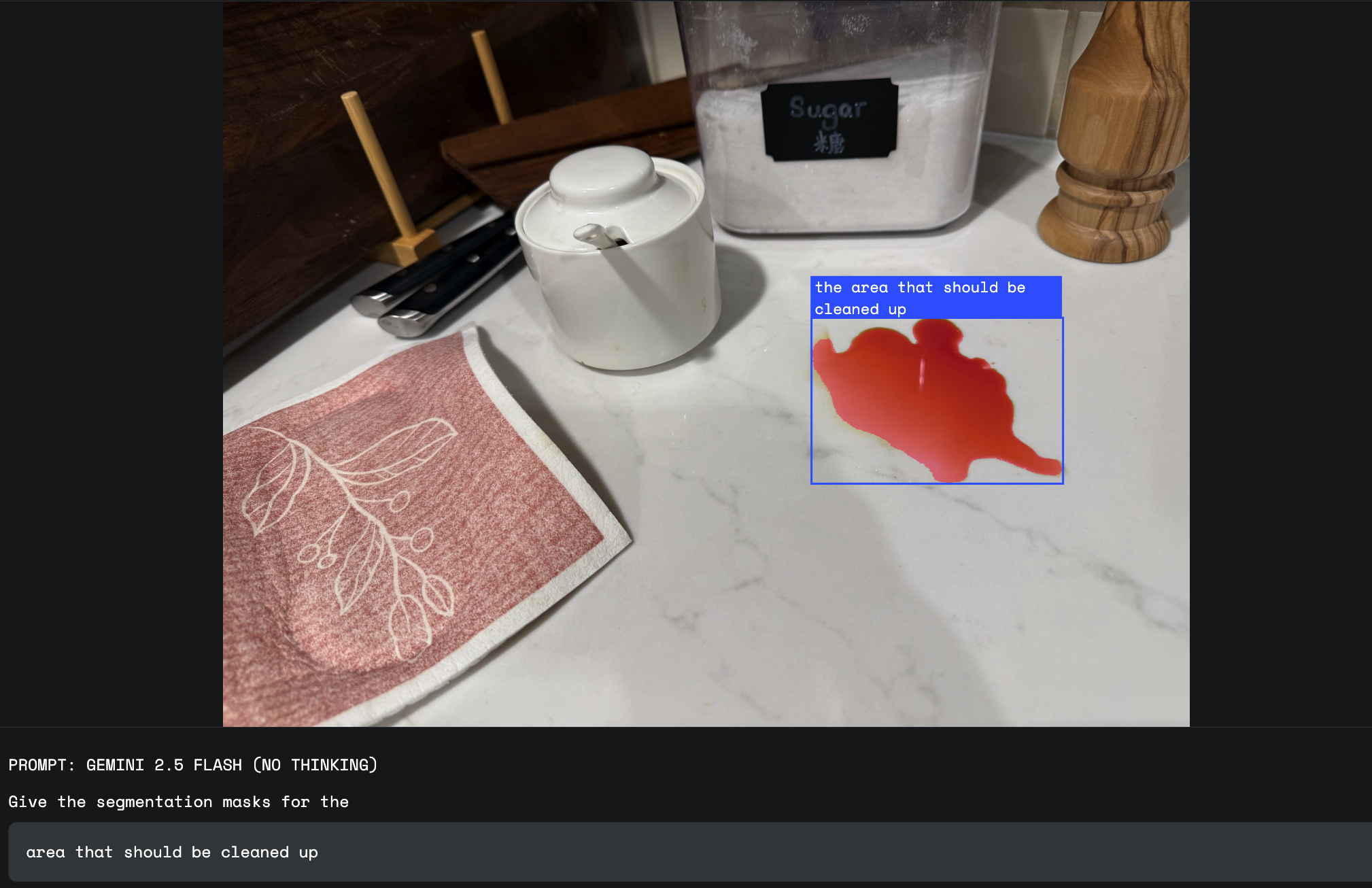On a kitchen counter, a natural language segmentation overlay highlights a spill in response to the abstract query, "area that should be cleaned up".