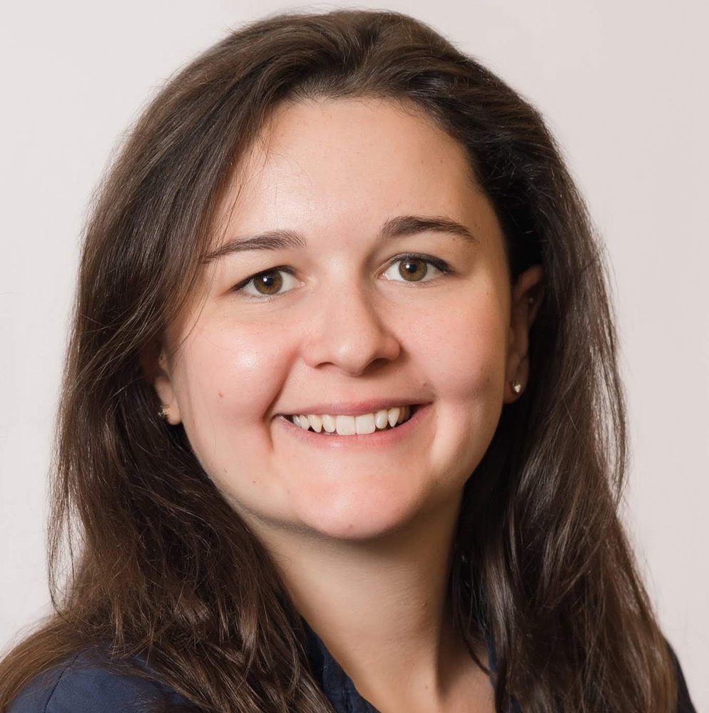 A photo of a woman with long brown hair smiling at the camera