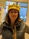 Alt text: Monica wearing a gold crown, gold beads, and a gray, Google-branded vest.