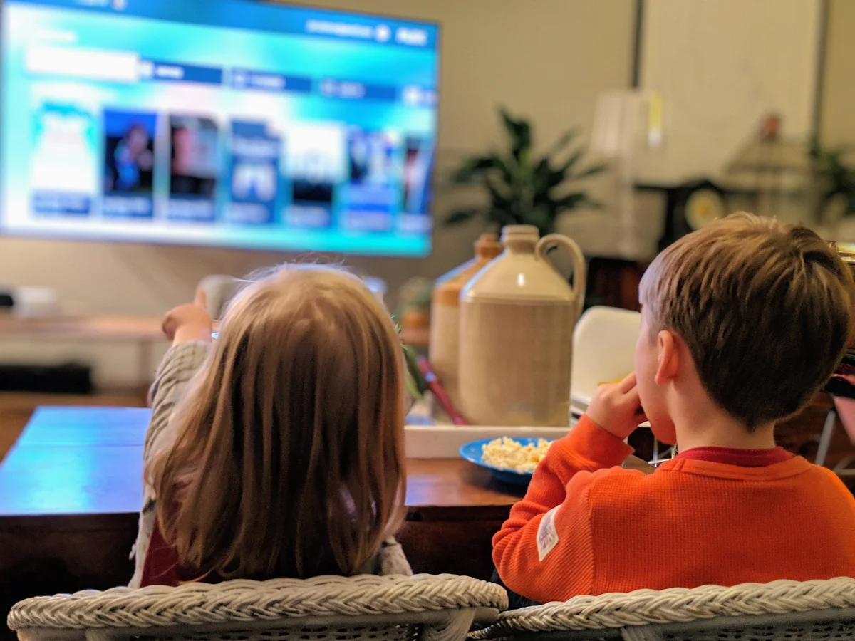 photo of two children sitting in a living room watching TV