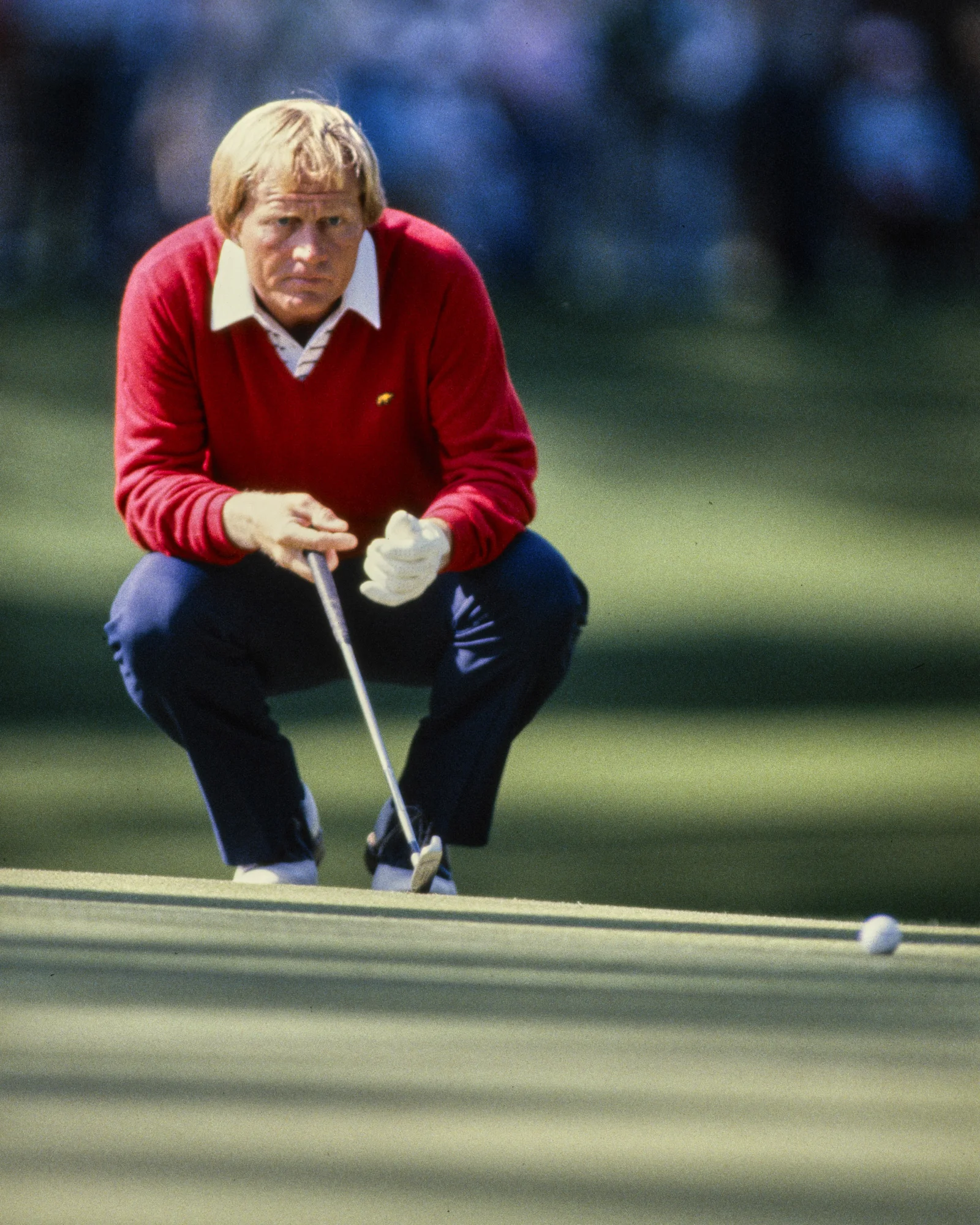 Jack Nicklaus crouching down on a golf course.