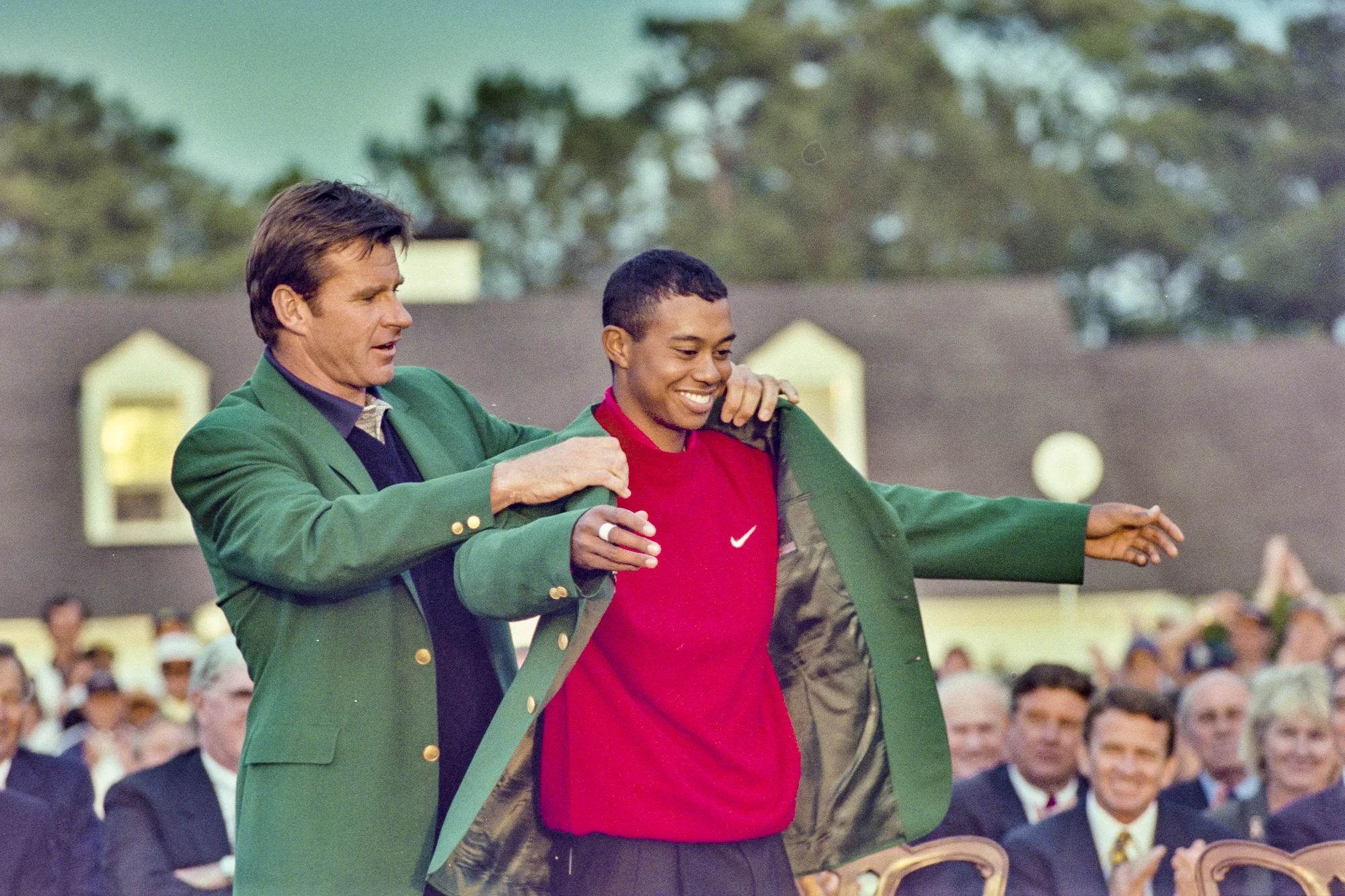 Tiger Woods being presented with the green jacket for winning a major golf tournament.