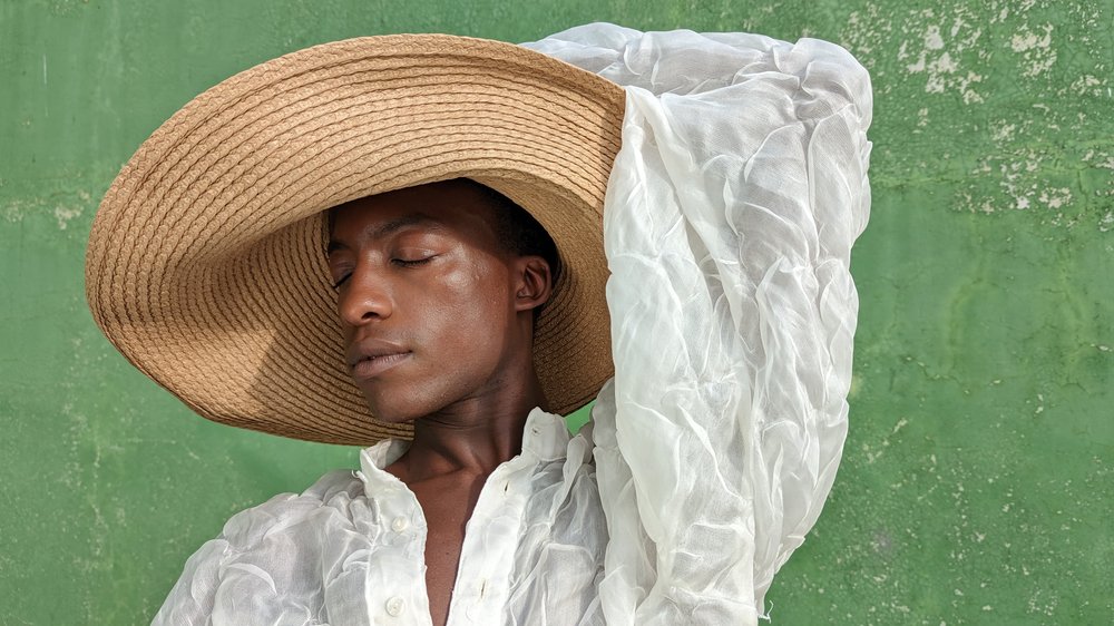 A person standing against a green wall looking away