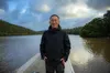 One man smiling on a small boat on a river