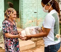 Senhora recebe cesta básica de representante da Amigos do Bem.