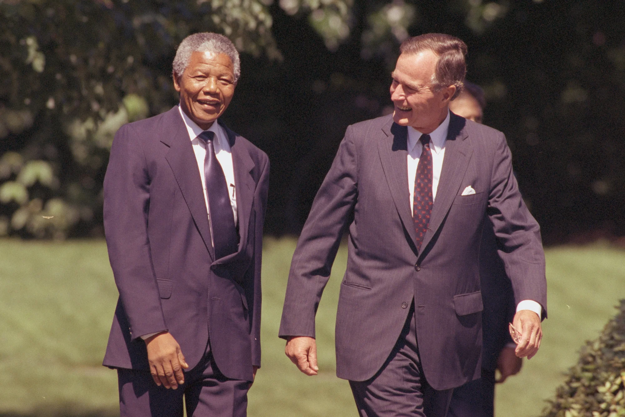 Nelson Mandela with George H.W. Bush walking and talking at the White House.