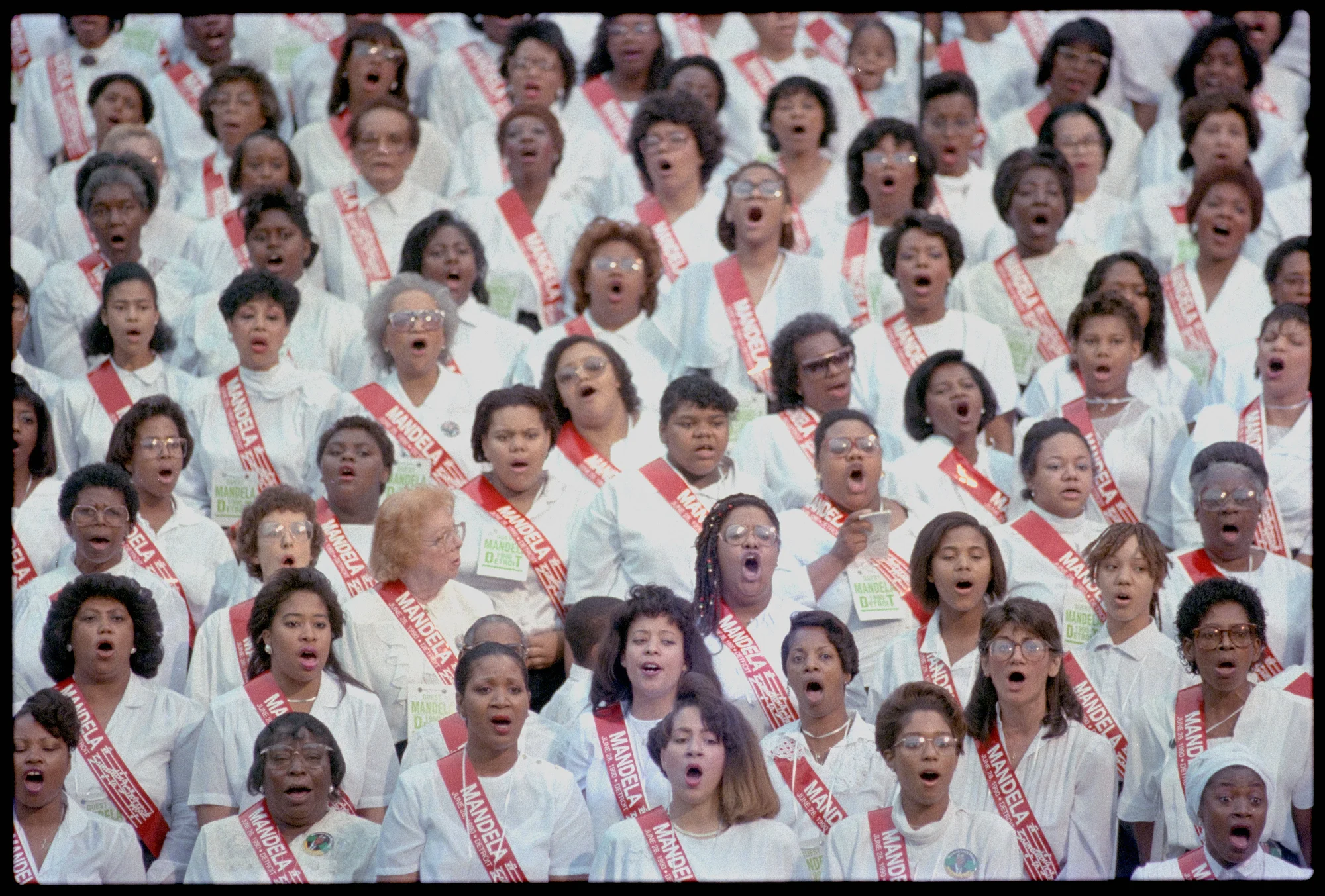 A group of choir singers wearing white shirts with sashes.