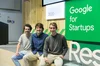 Zdjęcie Manuela Mariny Breysse, Jose Maríi Lillo Castellano i Iñigo Juantegui, współzałożycieli startupu Idoven, siedzących na krawędzi sceny. Po prawej stronie jasnozielony znak z białymi literami brzmi „Google dla start-upów”.