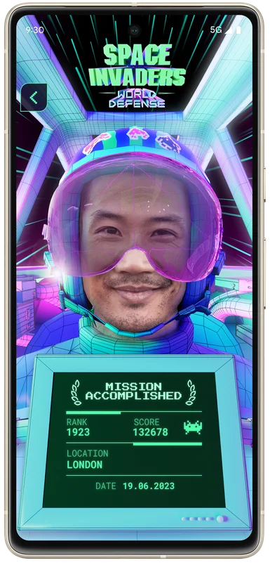 Japanese man taking an augmented reality selfie showing him as a pilot of the World Defense team and his rank and score he achieved in the game.