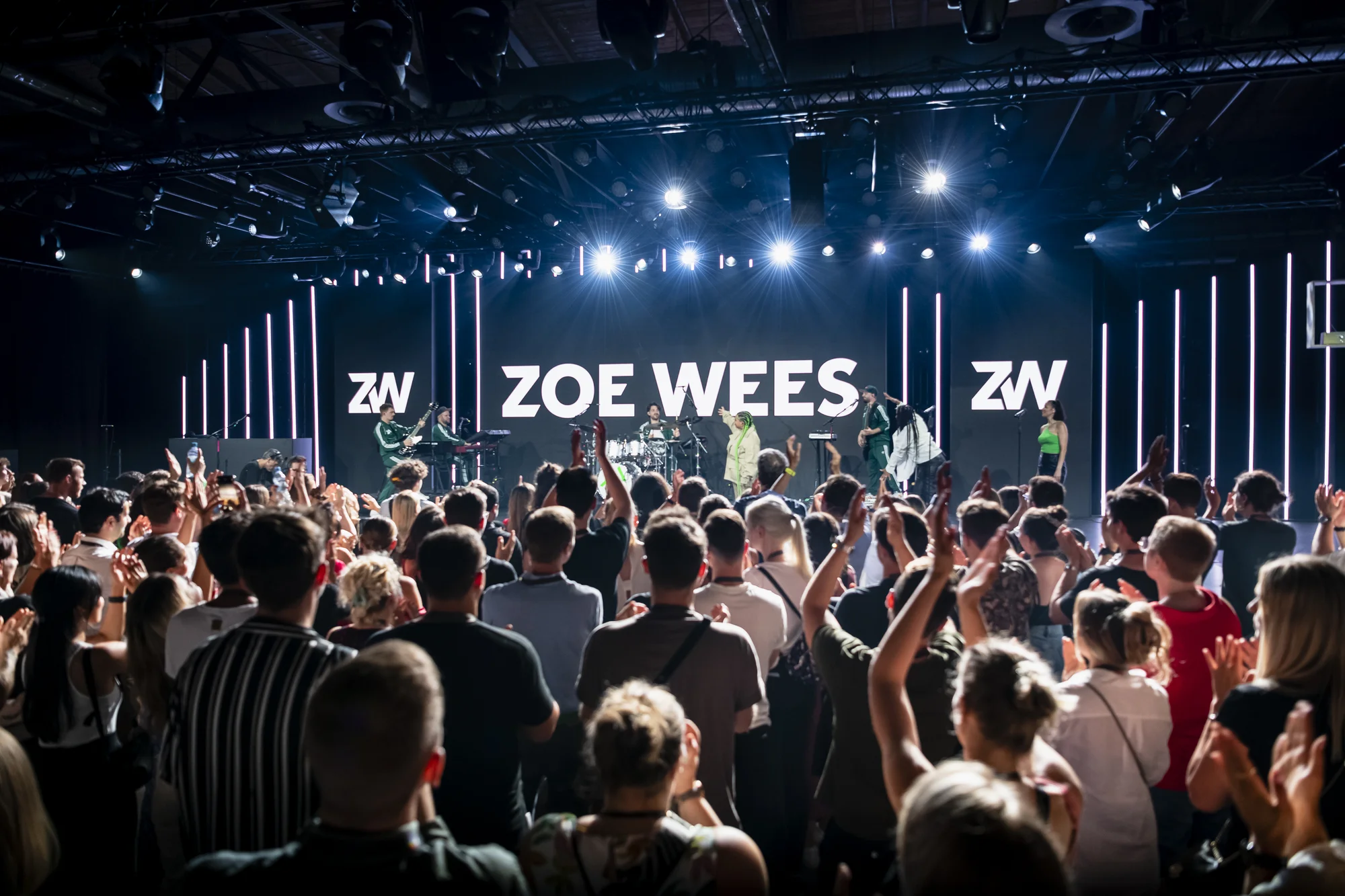 Eine große Traube Menschen steht vor einer Bühne. Im Hintergrund steht der Schriftzug "Zoe Wees".