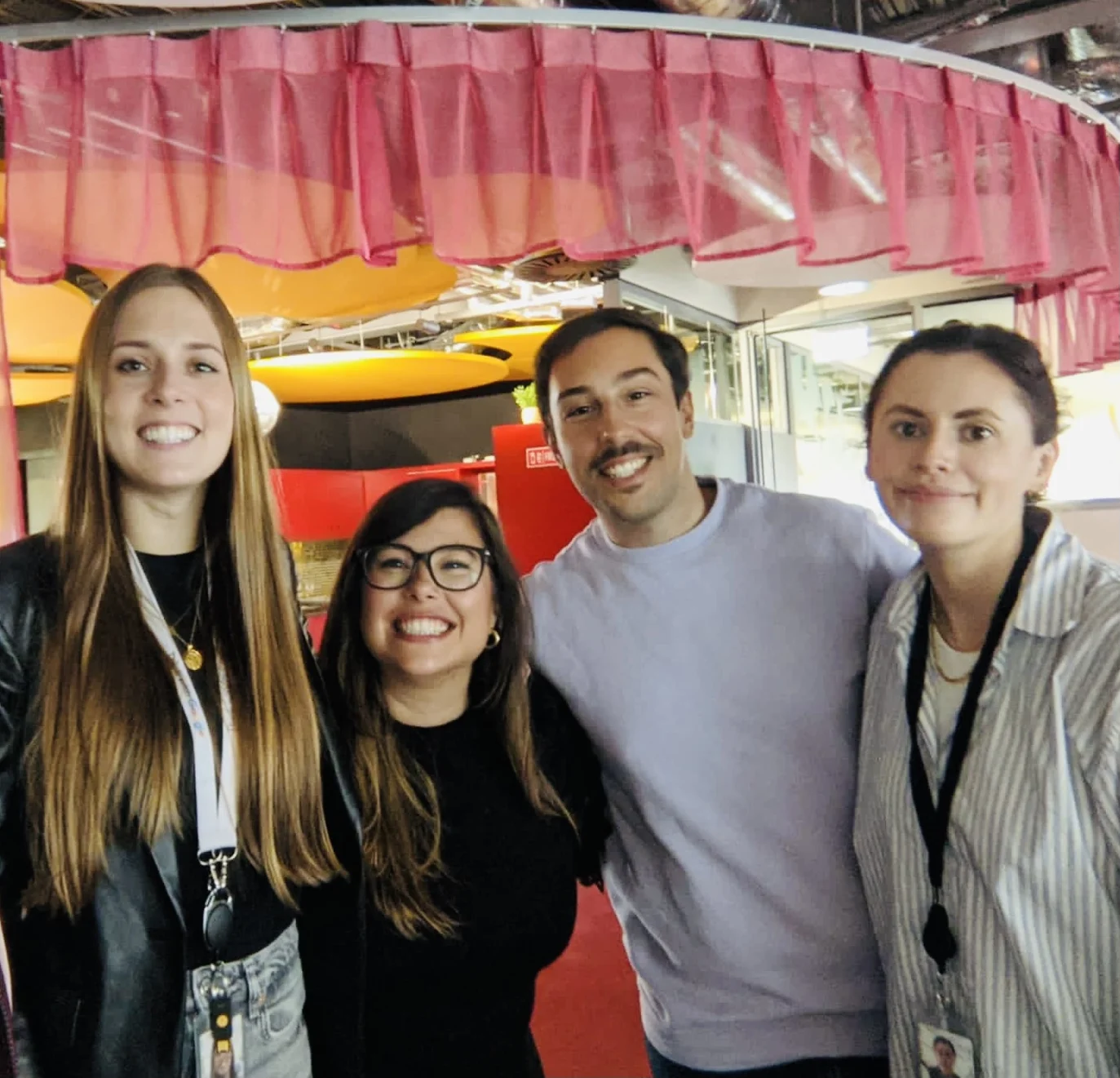 Desi auf einem Gruppenfoto mit Arbeitskolleg:innen und -freund:innen im Büro.