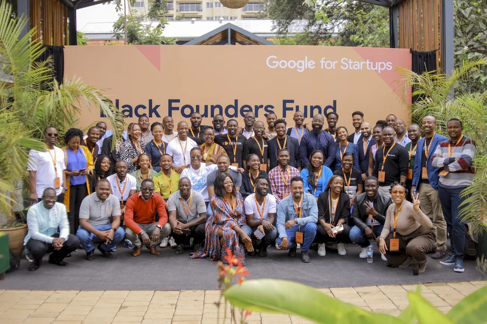 A photo of people standing together side by side in front of a banner with Google for startups Black Founder's Fund written on it