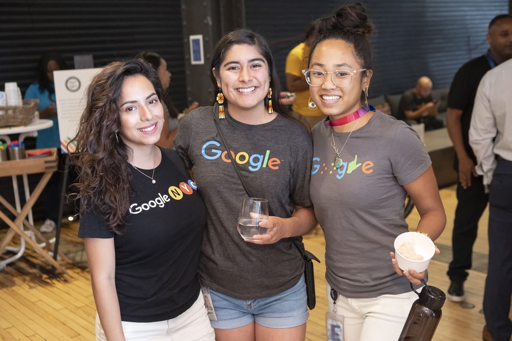 Three people wearing Google shirts at an indoor event.