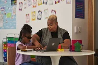 Teacher working with a student on a Chromebook