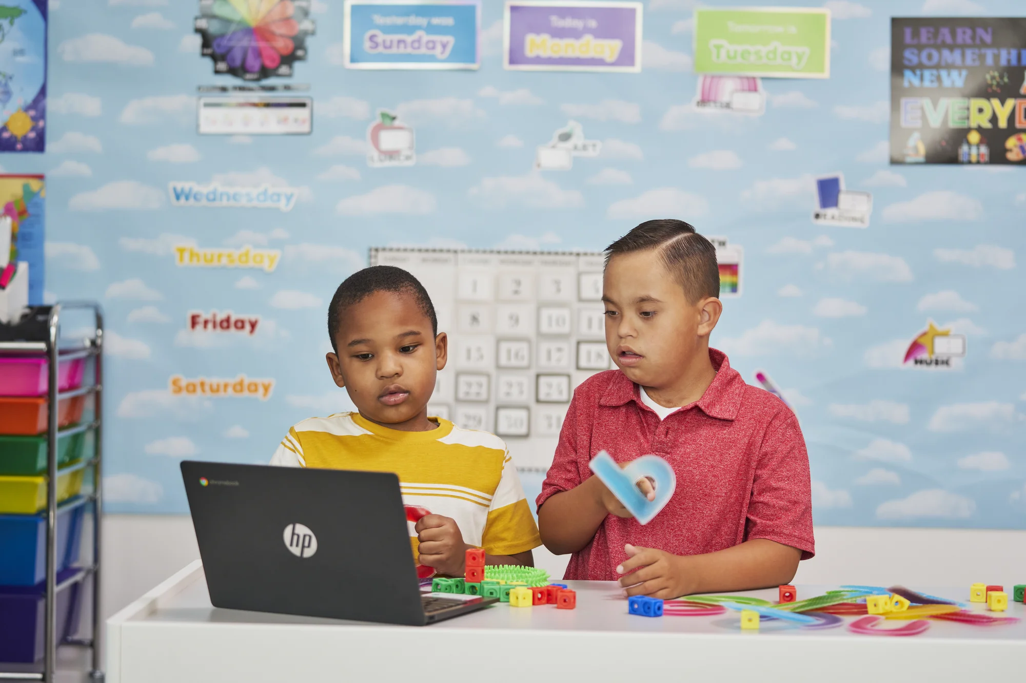 One autistic student and one student with Downs Syndrome working together in classroom on a Chromebook