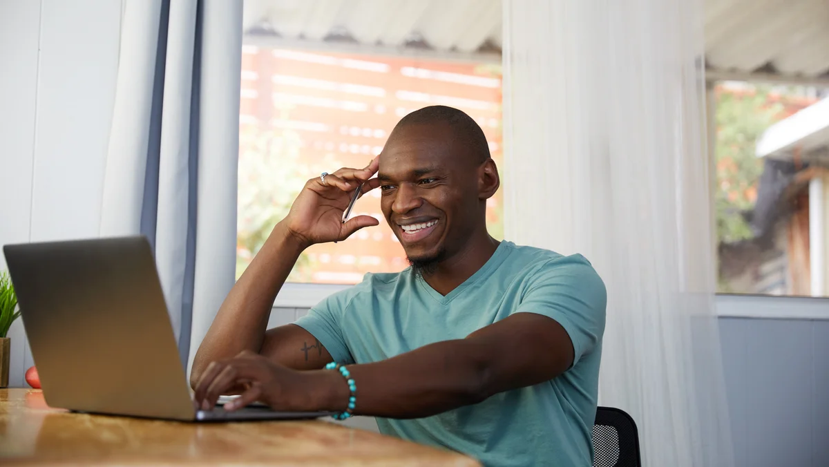 A man sitting at a desk looking at a laptop screen.