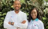 Zdjęcie Ikechukwu Arthura Anoke i Daisy Isiaho, współzałożycielek Zuri Health, od pasa w górę, ubranych w białe koszule z wyhaftowaną nazwą i logo firmy. W tle krzewy.