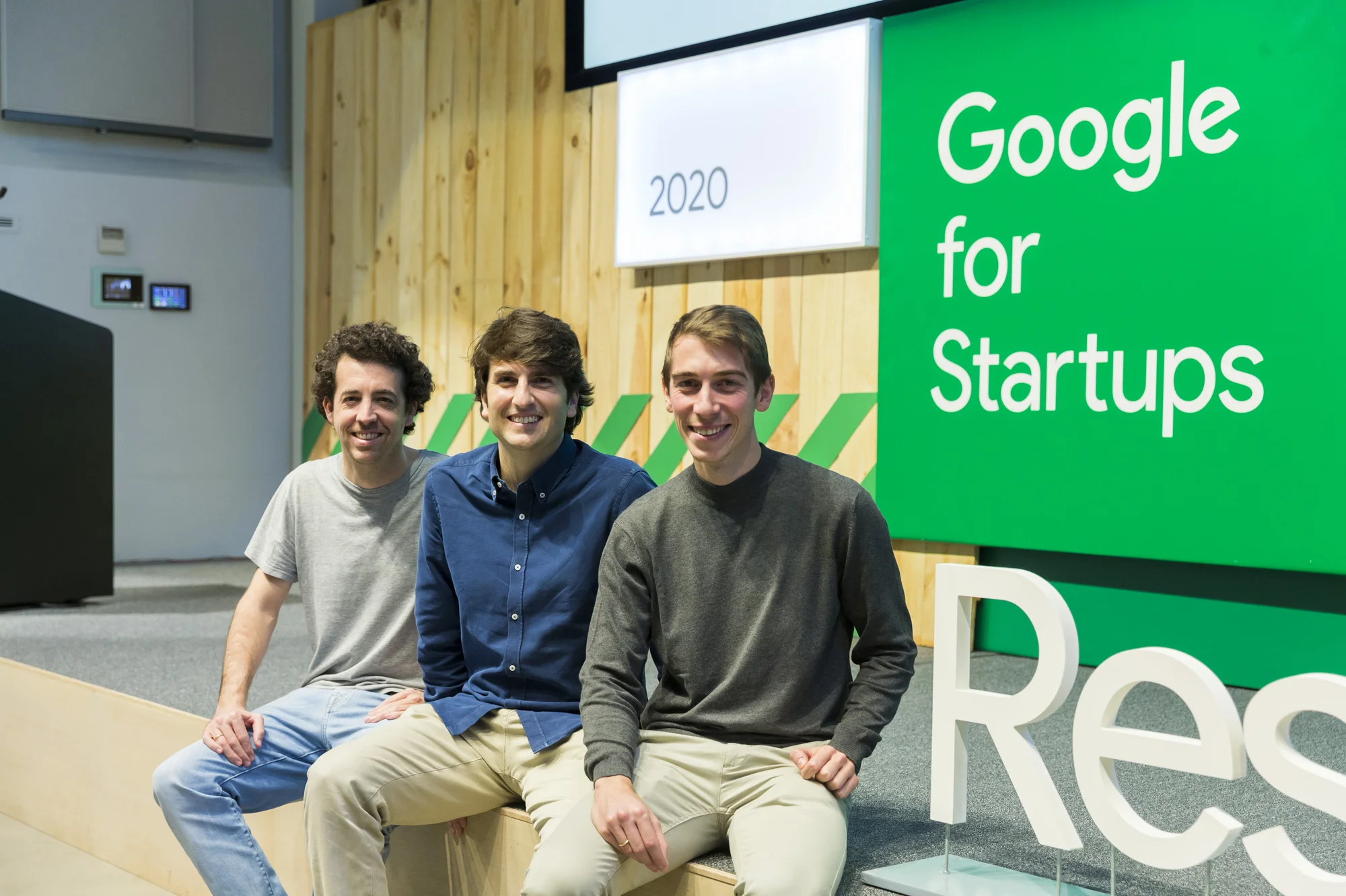 Manuel Marina Breysse, José María Lillo Castellano and Iñigo Juantegui, die Co-Gründer von Idoven, sitzen am Rand einer Bühne, im Hintergrund ist das Google for Startups-Logo zu sehen.